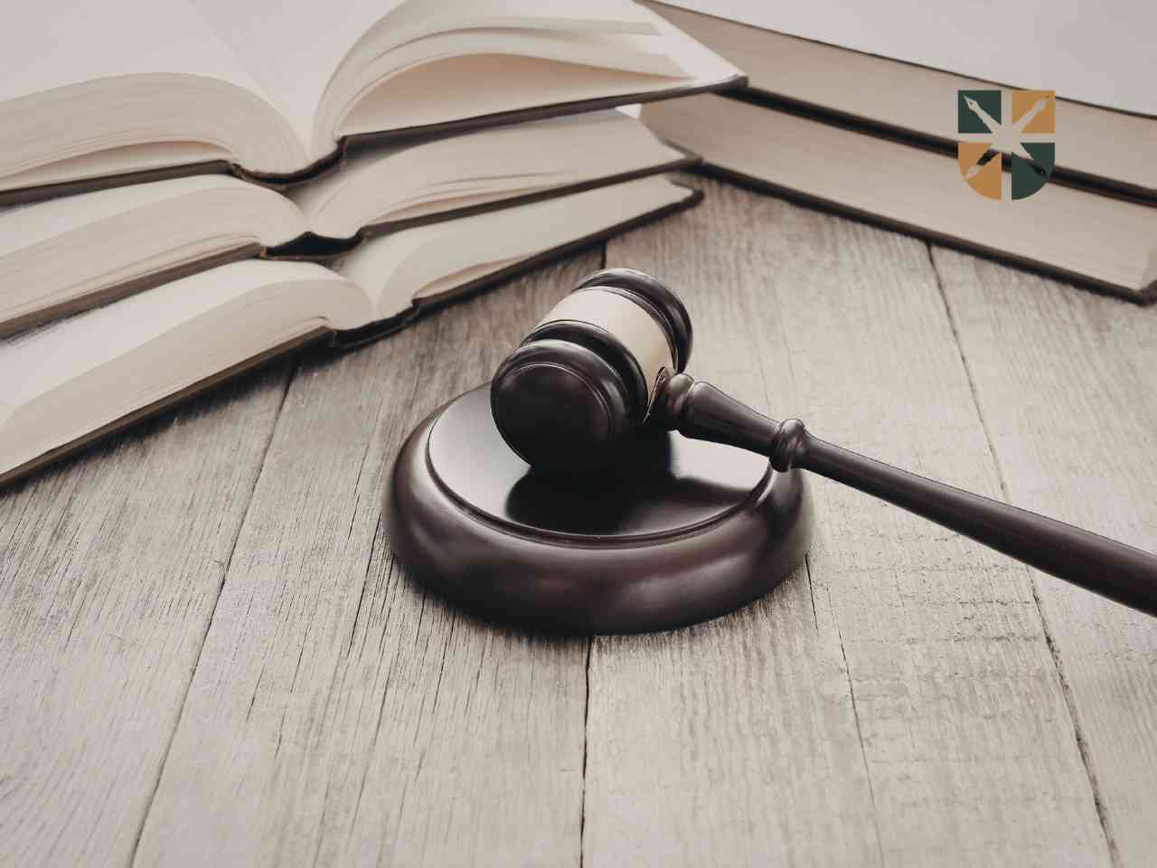 Drewniany młotek sędziowski leżący na stole obok otwartych ksiąg prawniczych – symbol prawomocnego wyroku.