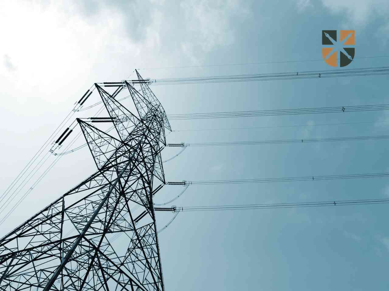 Wysoki słup energetyczny z liniami przesyłowymi przecinającymi działkę – ilustracja do tematu ograniczeń w zagospodarowaniu terenu.