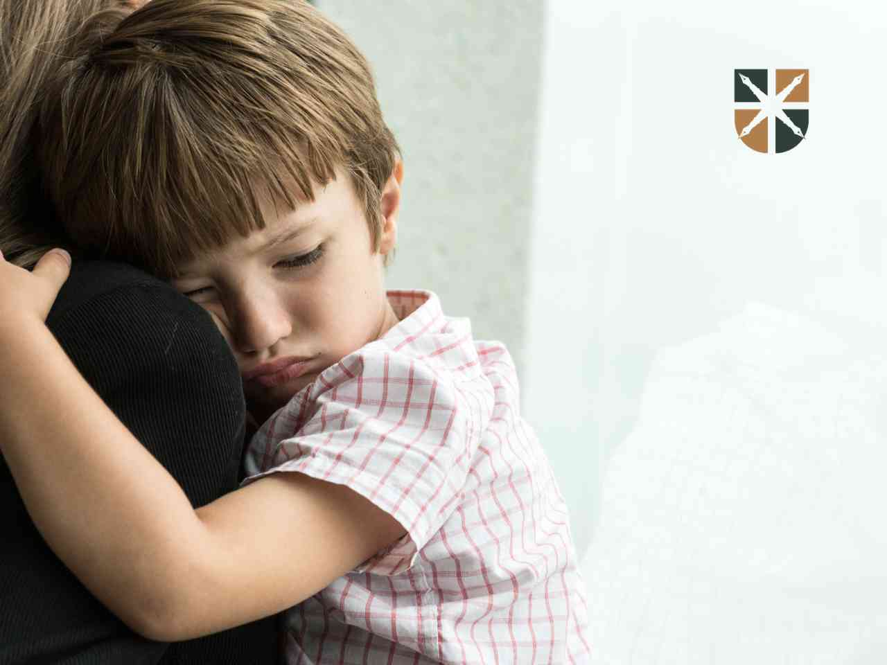 Smutne dziecko przytulające się do opiekuna po stracie bliskiej osoby.