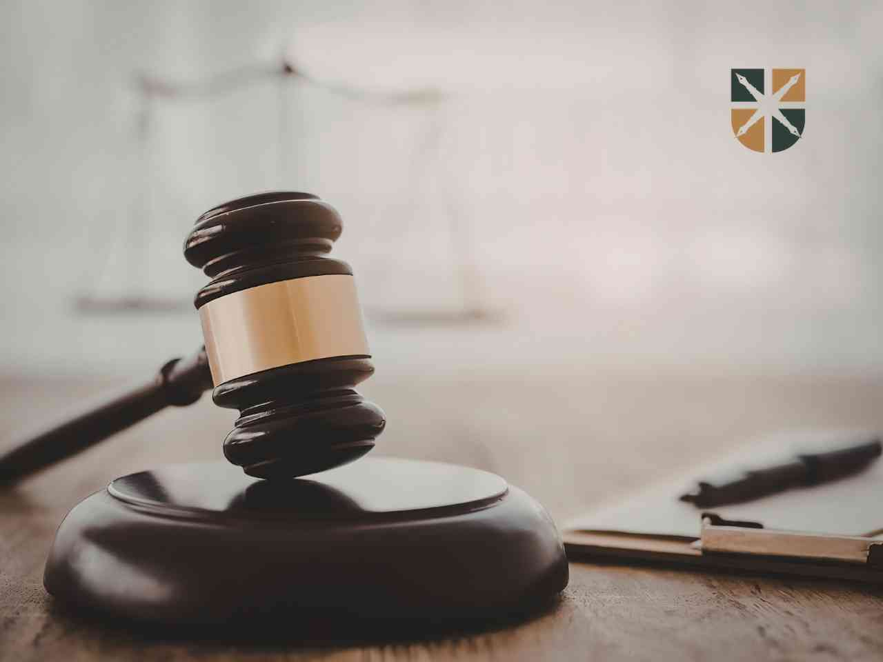 Sędziowski młotek na drewnianym stole symbolizujący sprawę o wyższe odszkodowanie w sądzie.