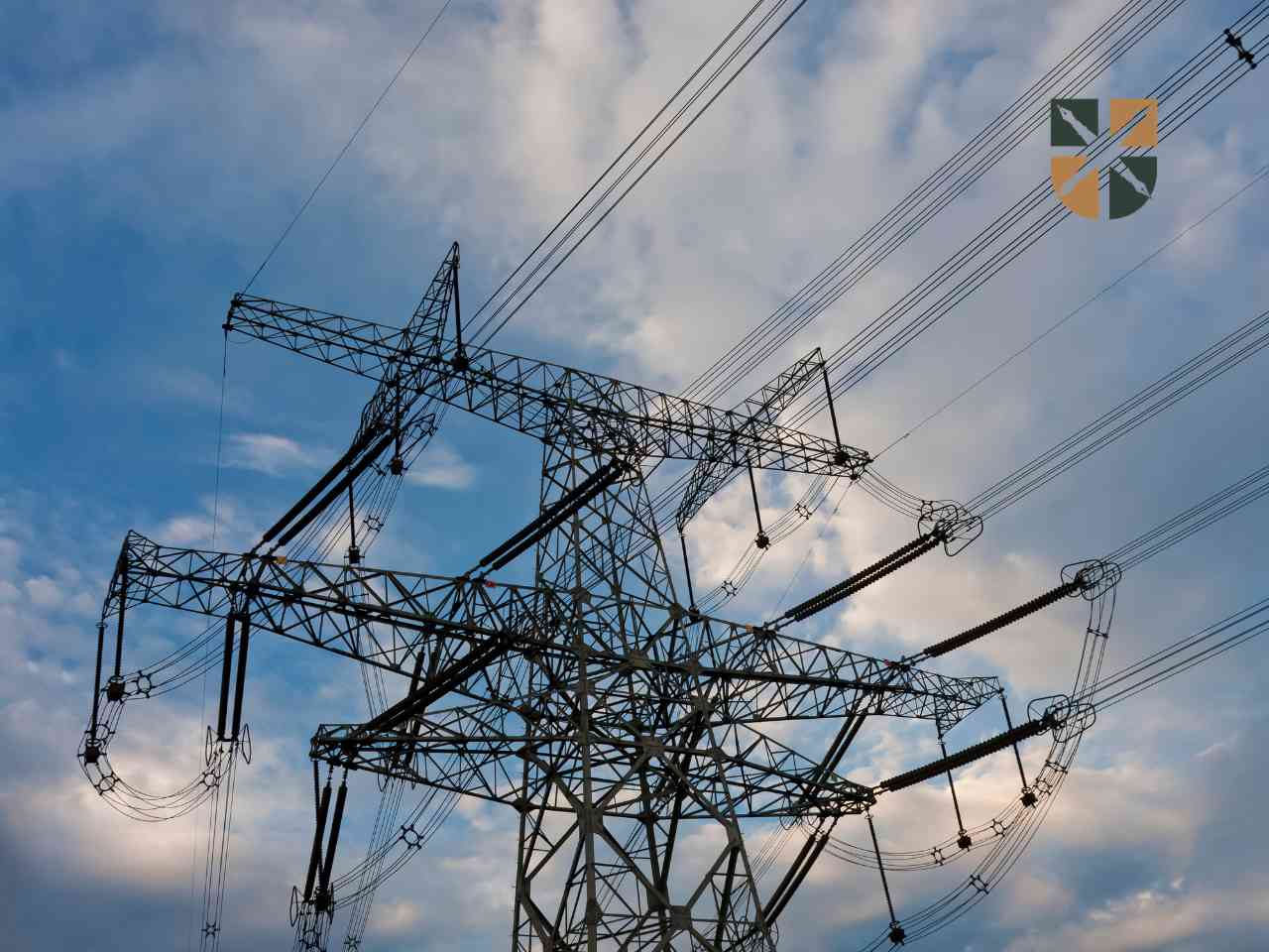 Zbliżenie na stalową konstrukcję słupa wysokiego napięcia na tle zachmurzonego nieba – inwestycja energetyczna na Śląsku.