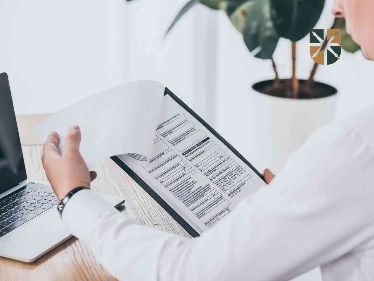 rekompensata-finansowa-wniosek Pracownik przegląda dokumenty na podkładce przy laptopie – ilustracja do wniosku o rentę rodzinną.