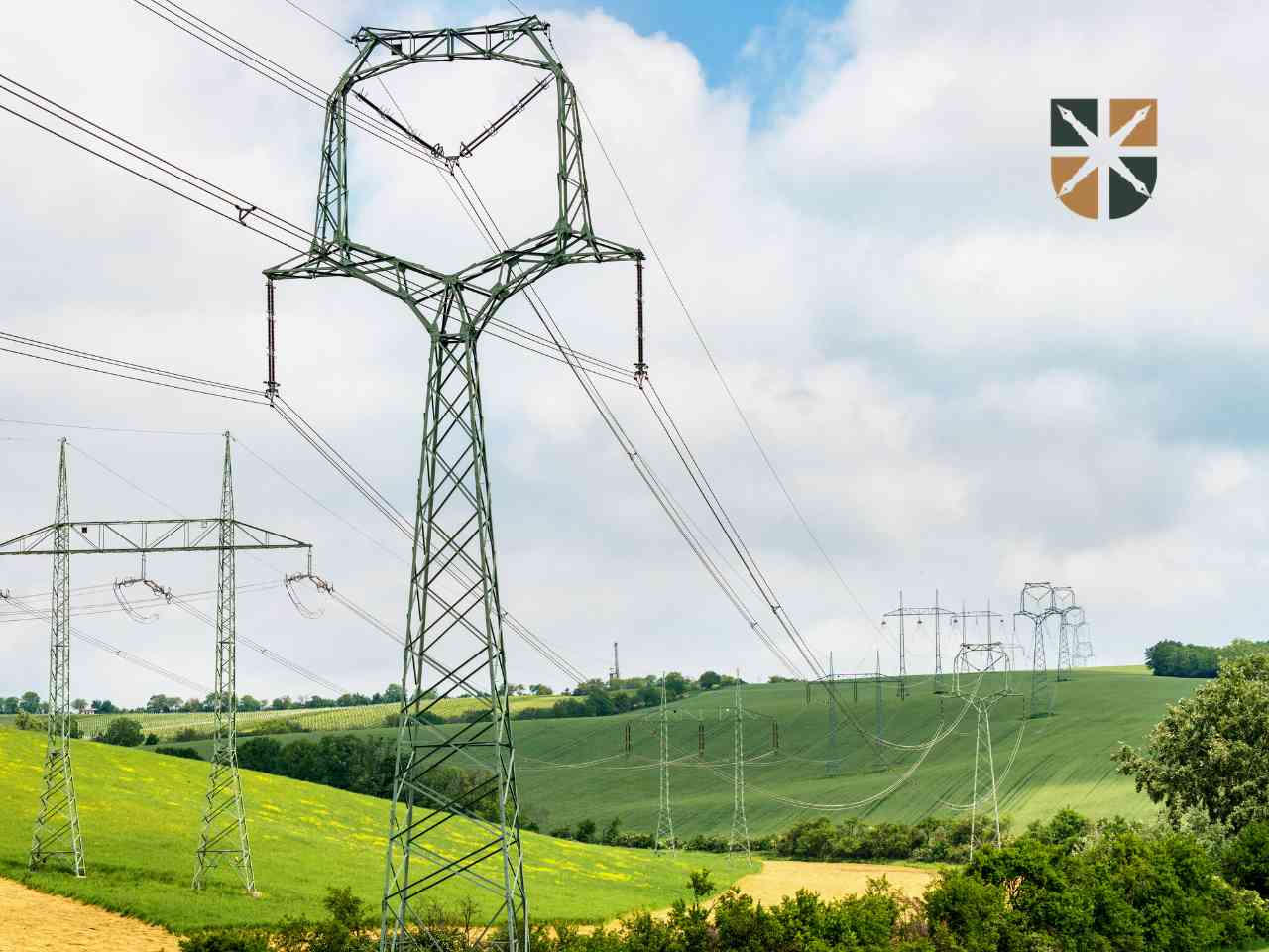 Słupy elektroenergetyczne wysokiego napięcia na tle zielonych pól – modernizacja infrastruktury przesyłowej