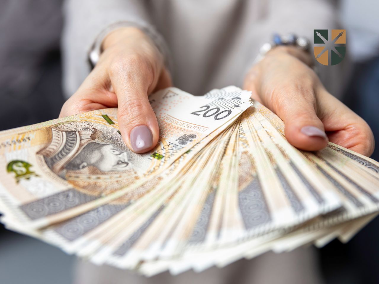 zadoscuczynienie-smierc-bliskiego Kobieta wyciąga przed siebie dłonie z wachlarzem banknotów o nominale dwustu złotych.