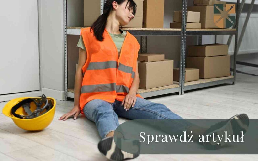 Poszkodowana pracownica w pomarańczowej kamizelce siedzi pod regałem w magazynie obok kasku