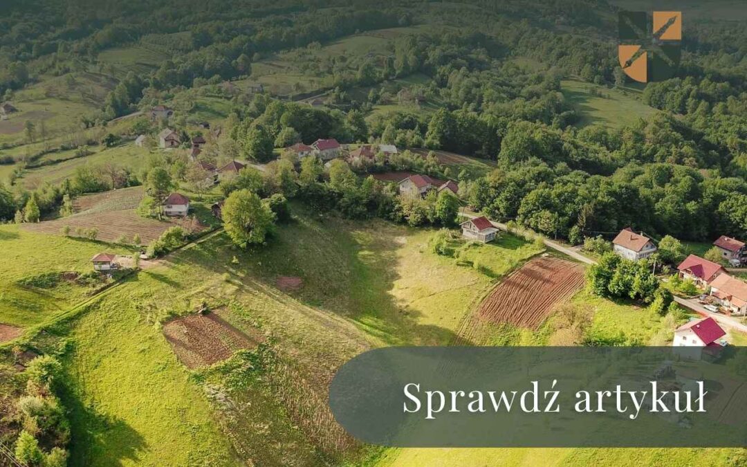Panorama wiejskiej miejscowości w dolinie otoczonej lasami i polami uprawnymi.