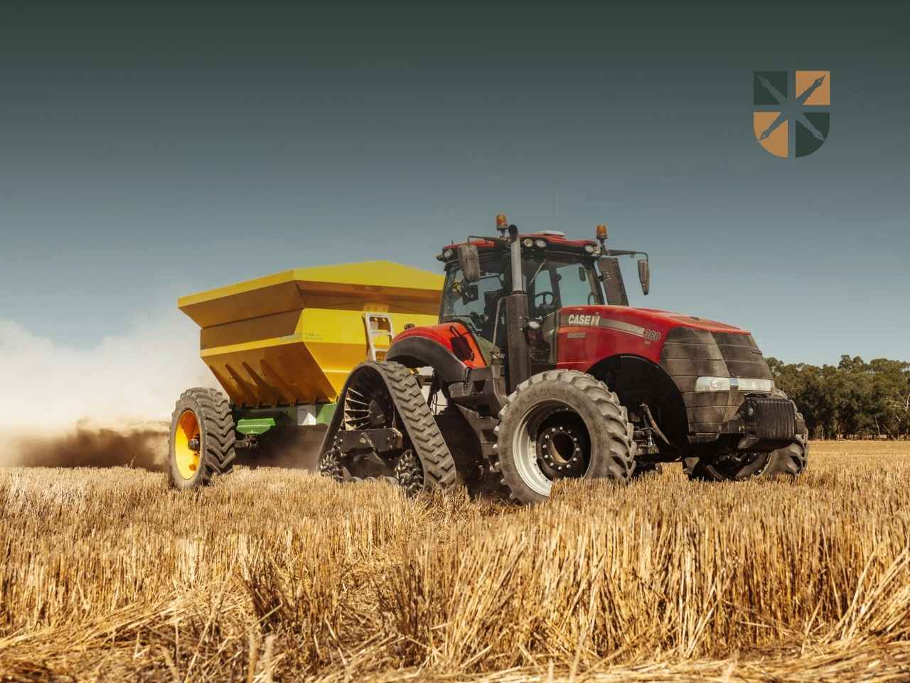 traktor-zniwa Czerwony ciągnik rolniczy marki Case na gąsienicach/kołach z żółtym rozrzutnikiem/siewnikiem pracujący na ściernisku.