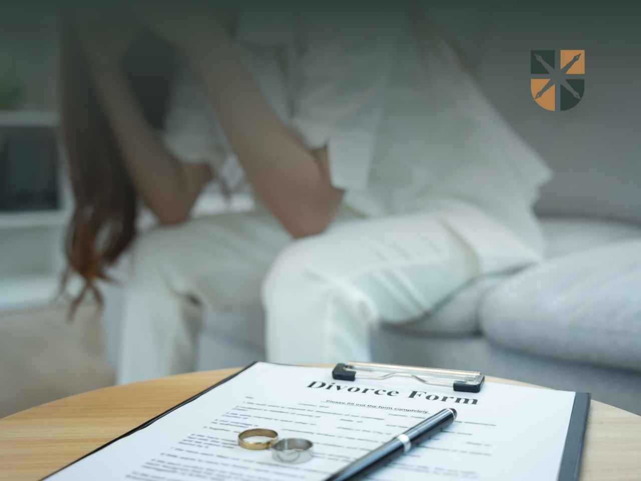 Załamana osoba siedząca w tle za formularzem rozwodowym i obrączkami na stole