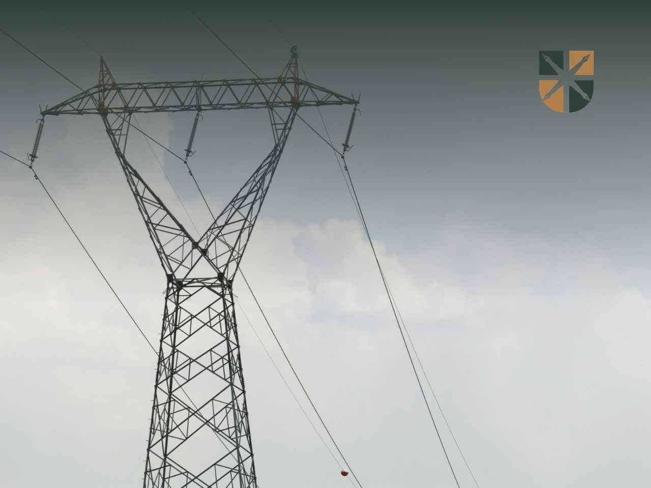 Słup i linie elektroenergetyczne stanowiące infrastrukturę przesyłową na tle zachmurzonego nieba.