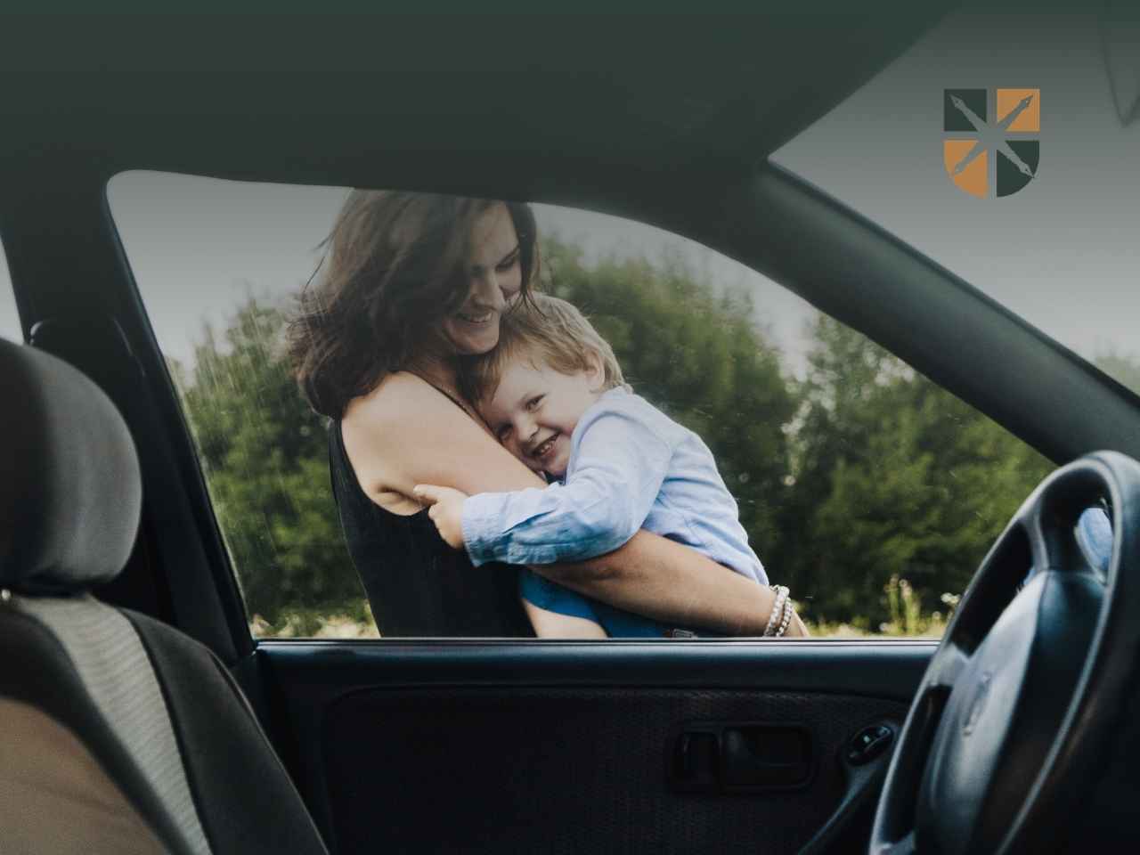 mama-z dzieckiem-auto Uśmiechnięta matka przytula małego syna widoczna przez uchyloną szybę samochodu.